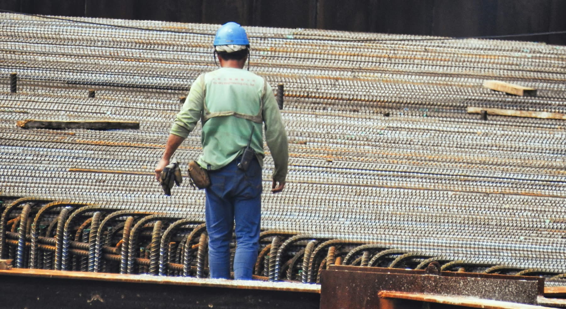 Obrero con casco camina sobre la armadura de hierro de una obra de hormigón