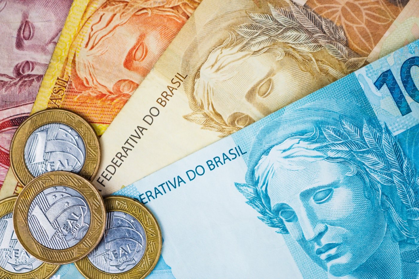 Billetes y monedas de real brasileño esparcidos sobre una mesa