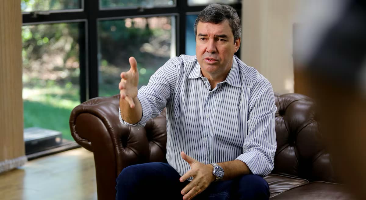 Hombre de camisa a rayas sentado en un sillón de cuero, gesticulando con la mano abierta durante una entrevista.