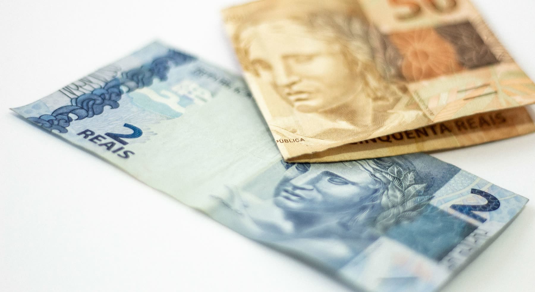 Uma nota de 2 reais e uma de 50 reais sobre fundo branco