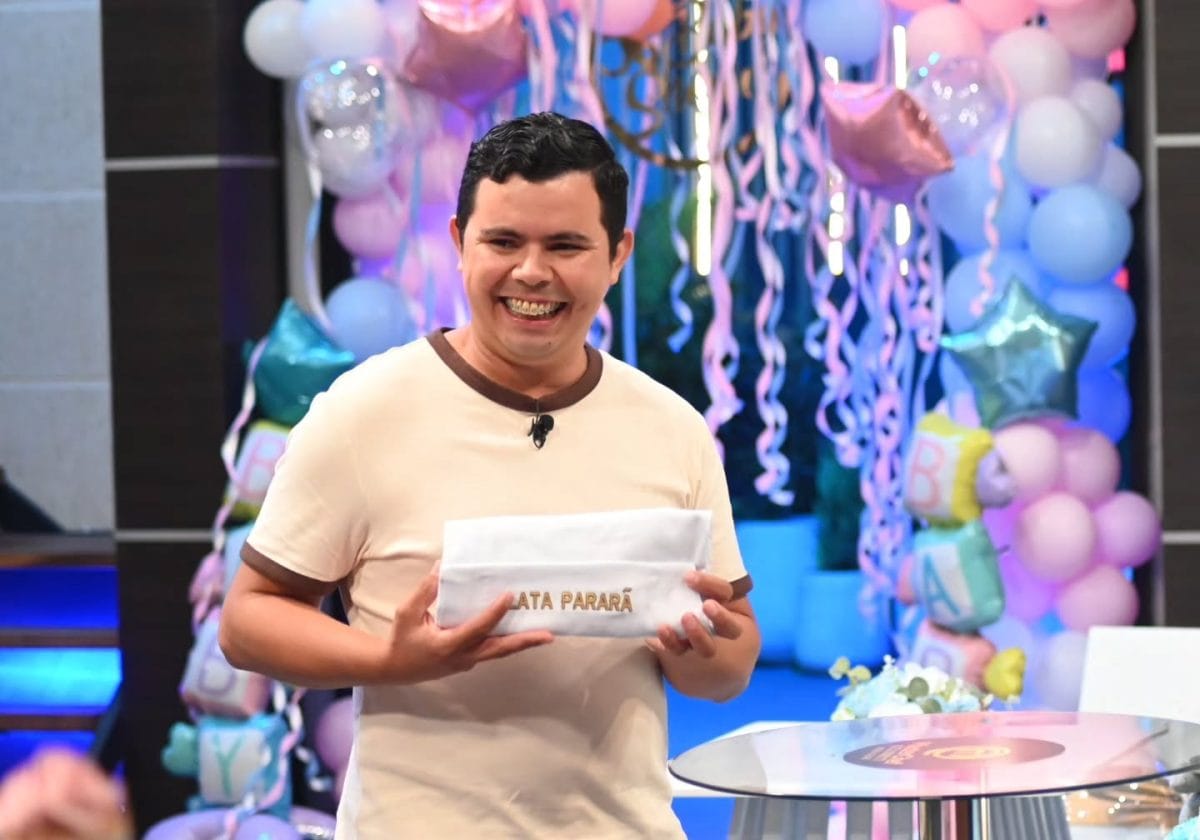 Latapararã sorri segurando um avental com o próprio nome no estúdio do MasterChef Celebrity Paraguay, decorado com balões