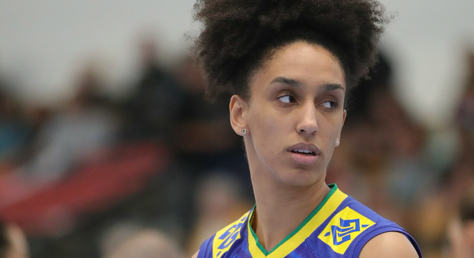 Jogadora da seleção brasileira de vôlei feminino, de uniforme azul e amarelo, durante partida