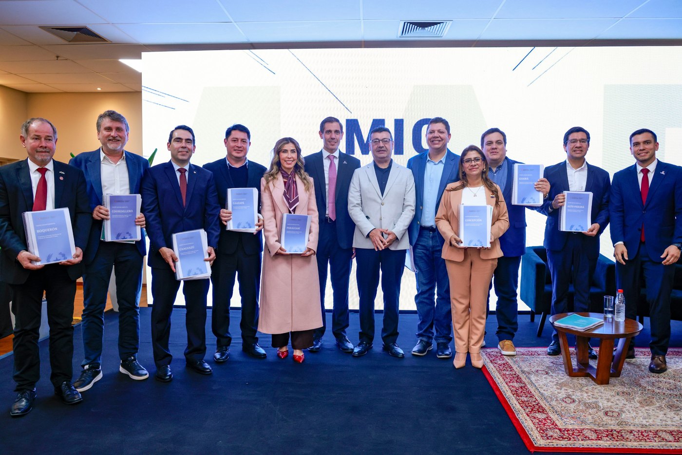 Autoridades paraguaias enfileiradas no palco do lançamento do MIC MAP, cada uma segurando um exemplar do documento, com o painel do Ministério da Indústria e Comércio ao fundo