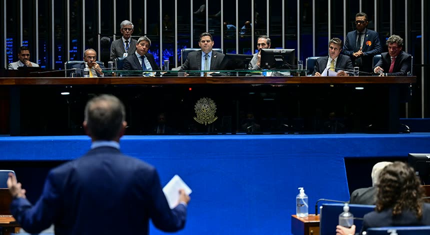 Plenário do Senado durante a sessão de 15 de outubro, com a mesa diretora ao fundo e um homem de terno, de costas e de pé, com papéis na mão.