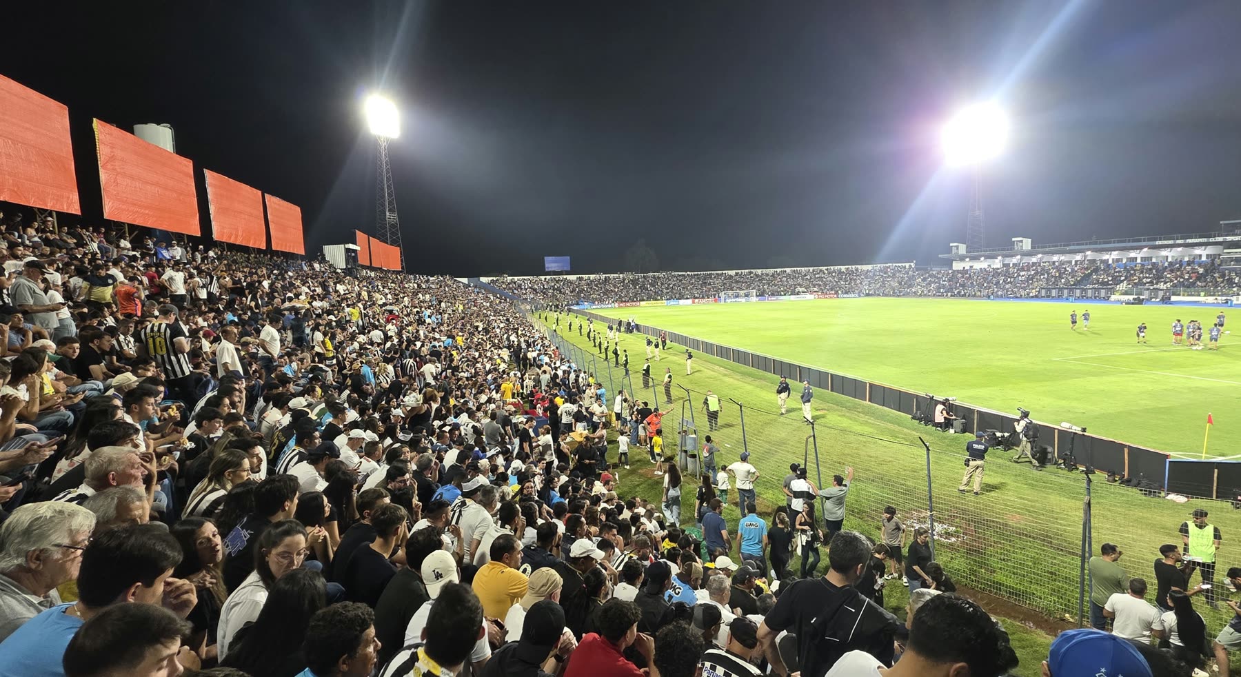 Tribuna llena y el césped iluminado durante el partido, de noche