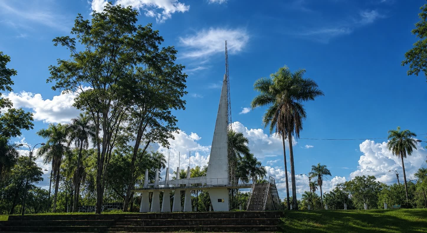 Monumento blanco en forma de aguja en el Parque Nacional Cerro Corá, entre palmeras y cielo azul