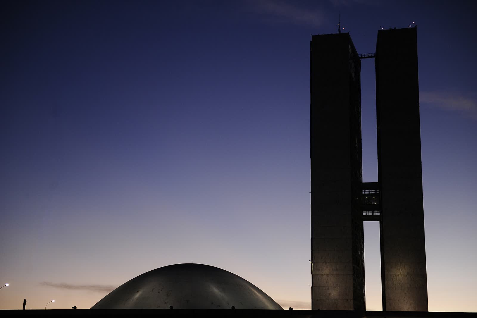 Cúpula do Senado e as duas torres do Congresso Nacional em silhueta, contra o céu azul do entardecer em Brasília