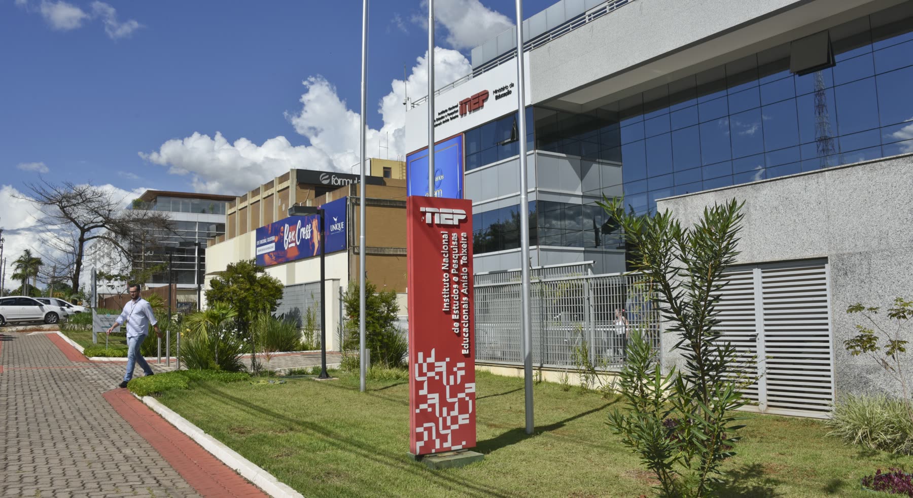 Fachada da sede do Inep, em Brasília, com a placa vermelha do instituto na frente do prédio de vidro e concreto.