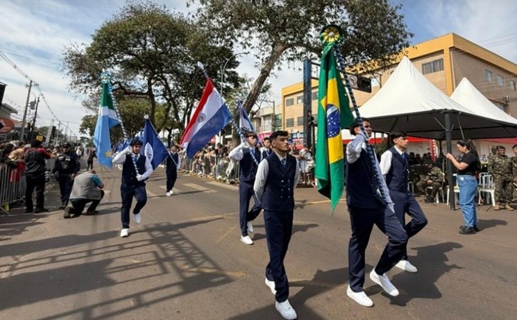 Estudantes de uniforme azul desfilam na Avenida Brasil carregando as bandeiras do Brasil, do Paraguai e de Mato Grosso do Sul