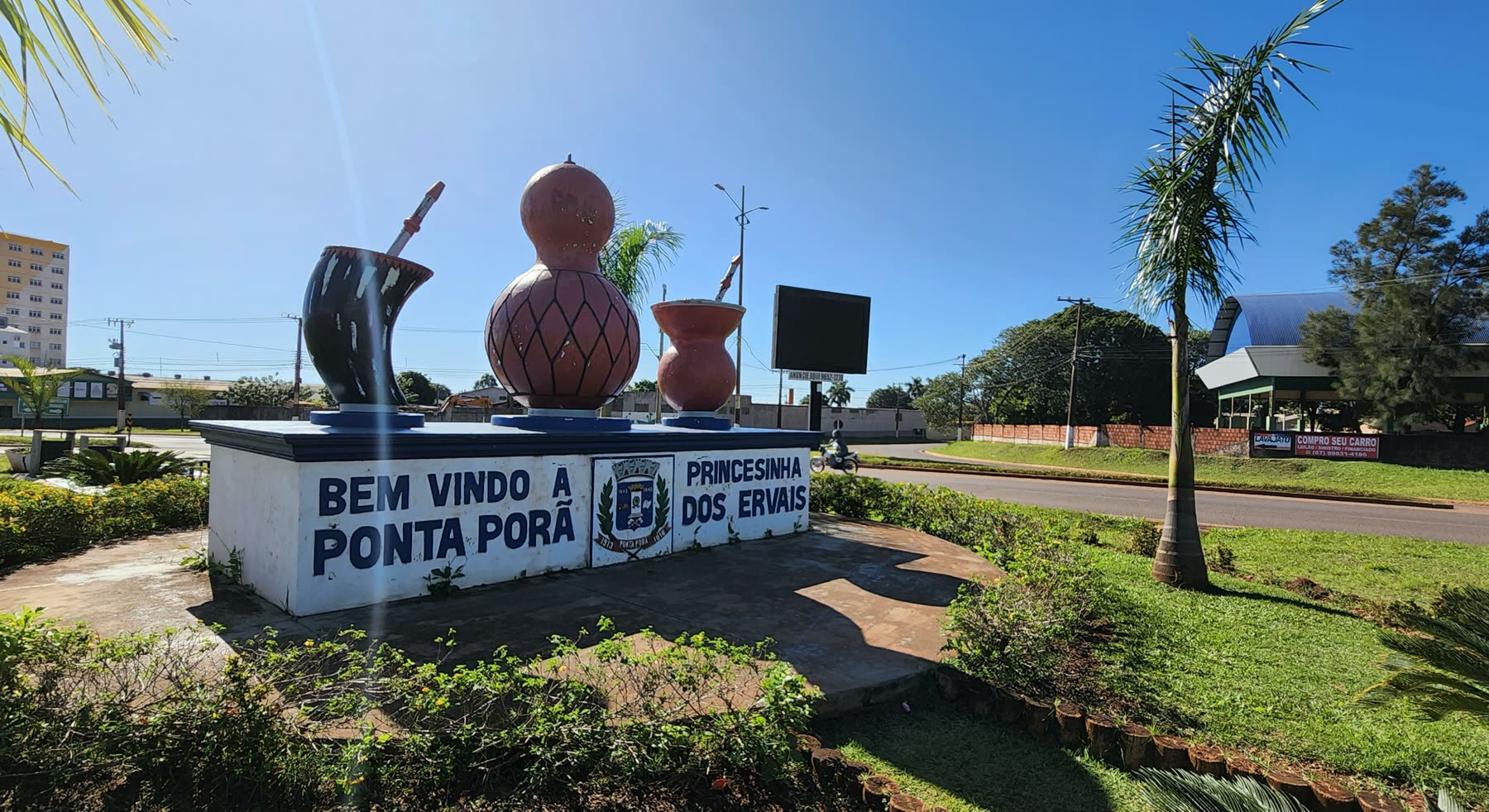 Pórtico de boas-vindas a Ponta Porã com esculturas de cuia e bomba de chimarrão, sob céu azul sem nuvens.