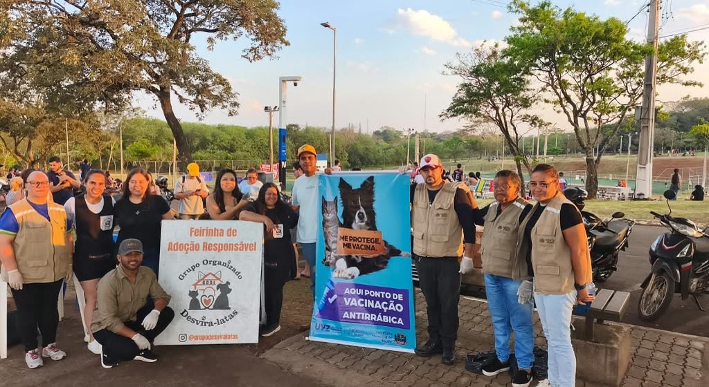Equipe de vigilância de zoonoses e voluntários posam com banner de ponto de vacinação antirrábica no Parque dos Ervais