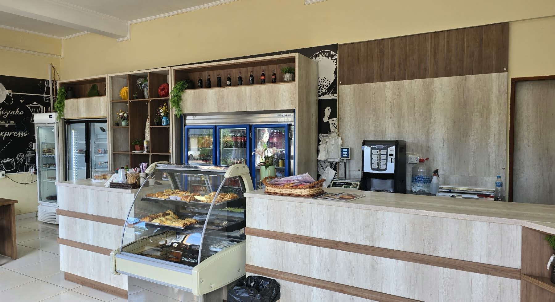 Mostrador de atención con vitrina refrigerada de dulces y salados, máquina de café y heladeras de bebidas al fondo