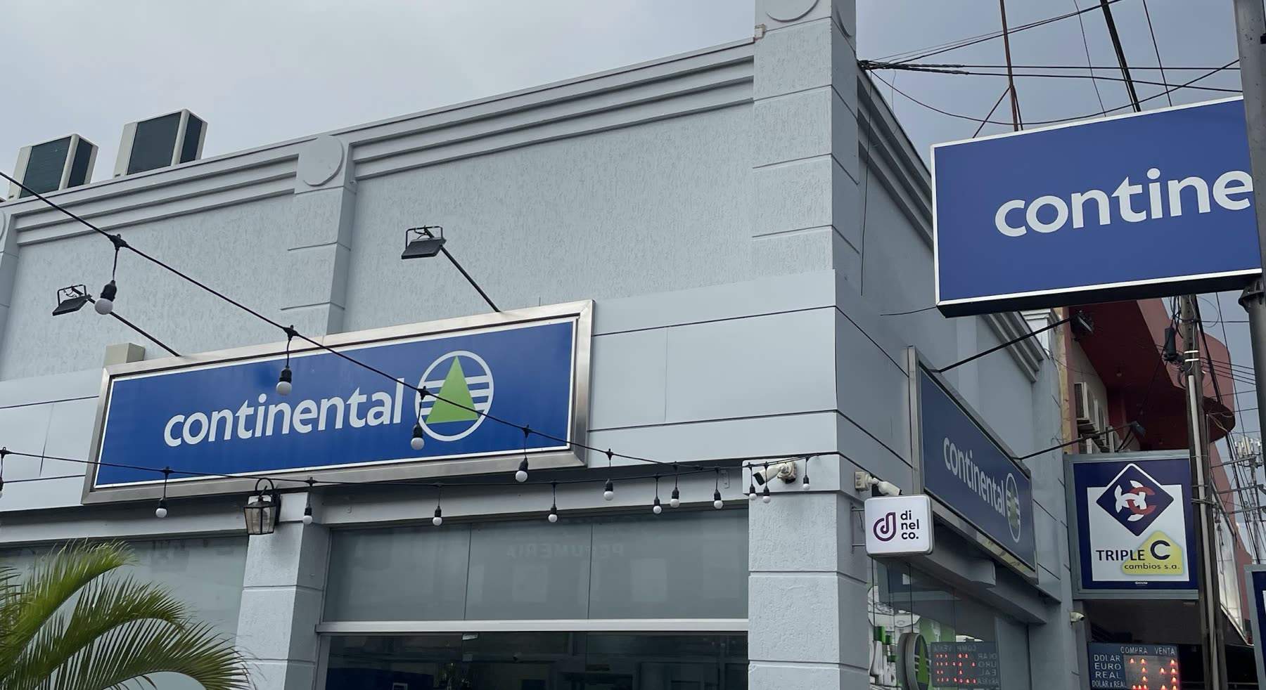Prédio cinza de esquina com duas placas azuis do Continental, uma na parede e outra perpendicular à calçada