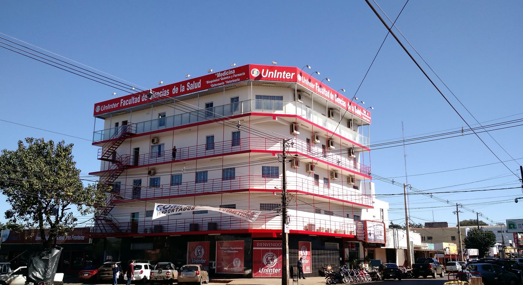 Edificio blanco y rojo de cuatro pisos con el letrero Uninter y la franja de la Facultad de Ciencias de la Salud, con escalera exterior roja en el lateral