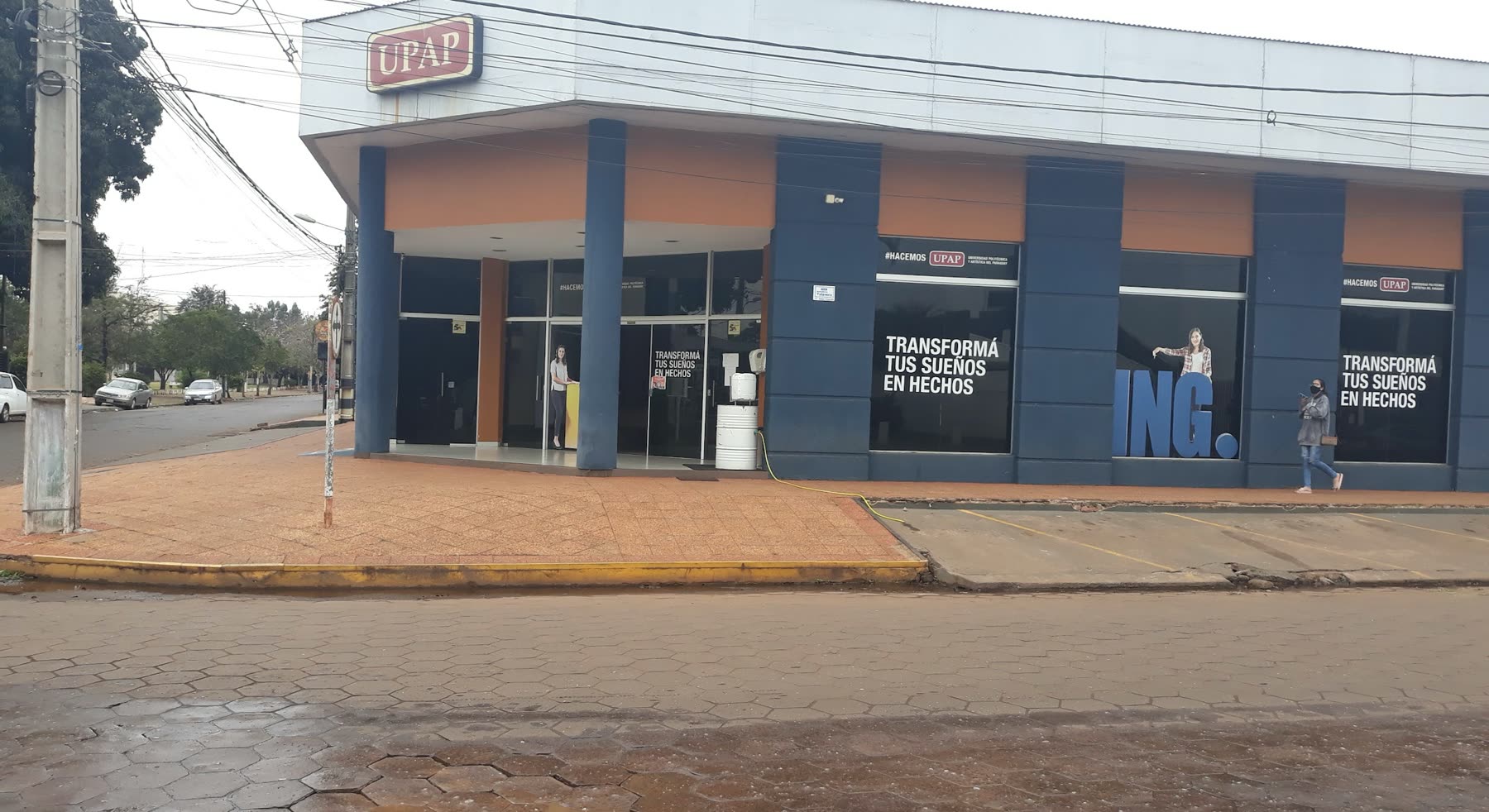 Edificio de esquina con el letrero UPAP en lo alto y vidrieras oscuras estampadas con la frase Transforma tus sueños en hechos
