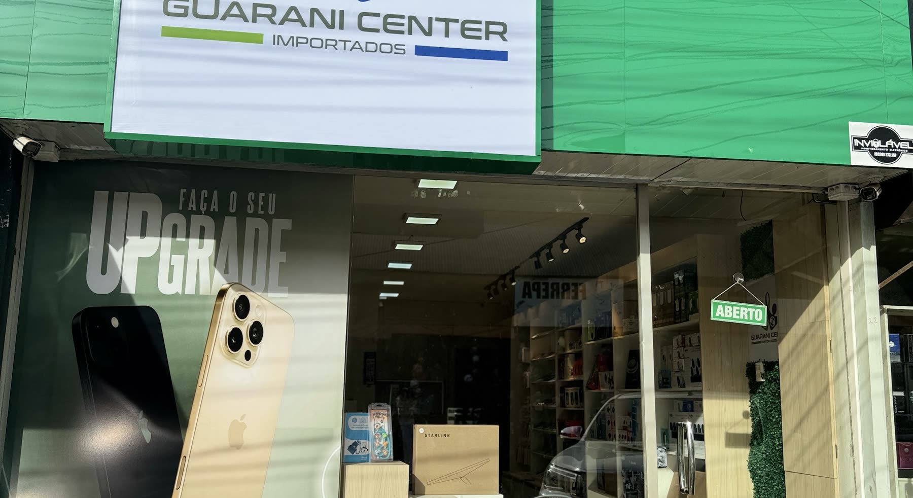 Local con el letrero Guarani Center Importados y una vidriera estampada con un celular grande y la frase Faça o seu upgrade, junto al cartel Aberto